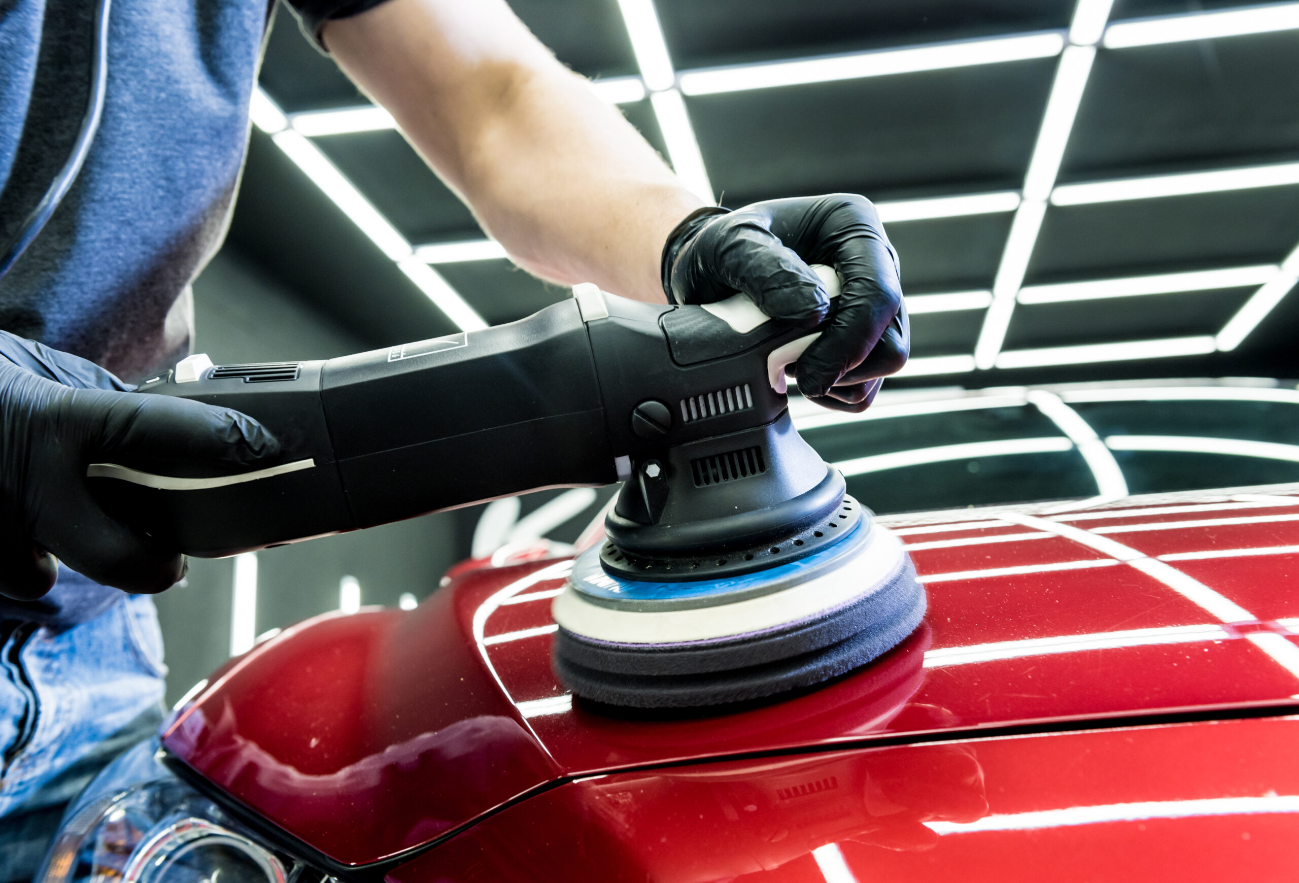 Car service worker polishes a car details with orbital polisher
